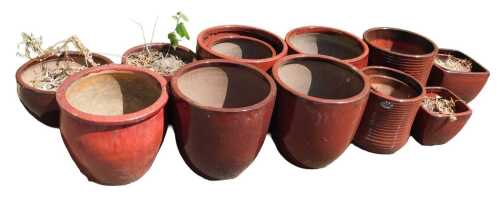 A group of red glaze terracotta plant pots, of plain form, of differing size and shape, the...
