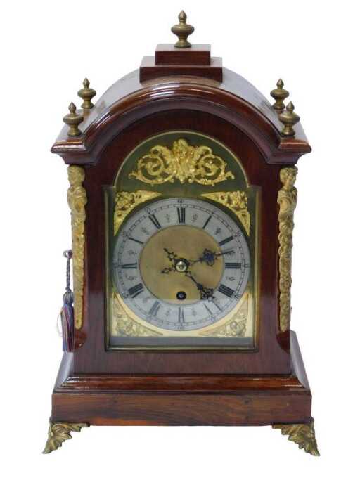 A Georgian-style rosewood-cased bracket clock, the arched top with brass finials and enclosed by...