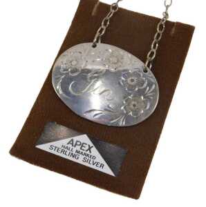 A 20thC sterling silver gin label, of oval form, etched with flowers, with chain on apex...
