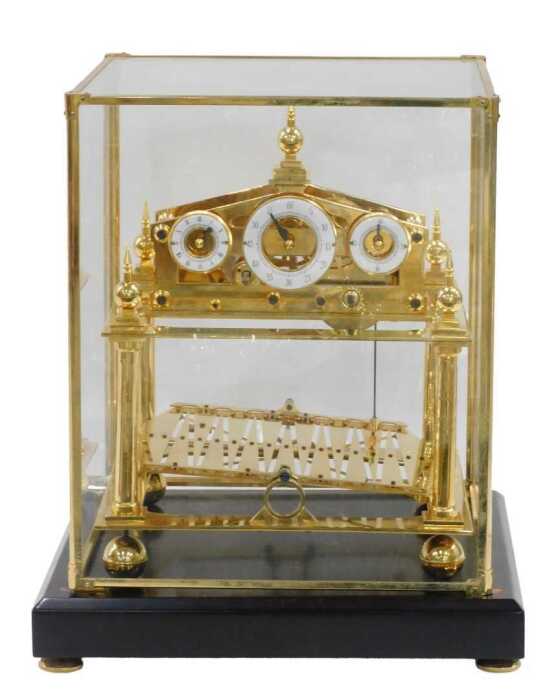 A 20thC Congreve rolling ball clock, in a highly elaborate gilt brass case, surmounted by an orb...