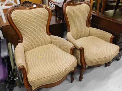 A pair of Victorian style walnut spoonback chairs, with carved shell backs, shaped arms and...