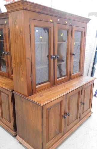 A stained pine three drawer glazed display cabinet, with triple cupboard beneath, and a similar...