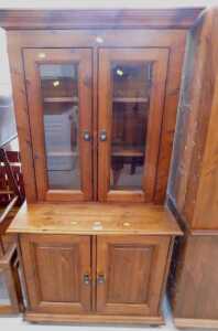 A stained pine three drawer glazed display cabinet, with triple cupboard beneath, and a similar... - 2