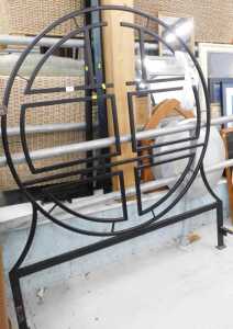 An iron double bed frame, with elaborate circular headboard, shaped footboard, slats and supports.