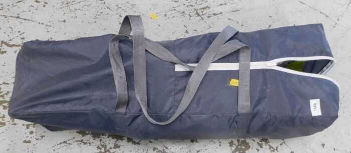 A travel cot in canvas bag.