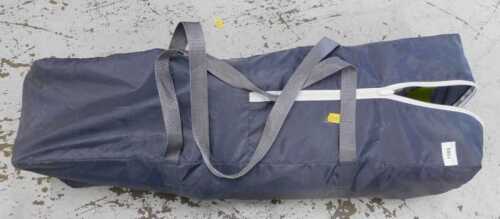 A travel cot in canvas bag.