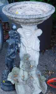 A classical design bird bath, a garden statue of a lady, and another.