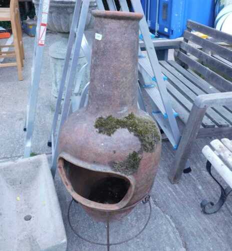 A chiminea fireplace fire pit on iron stand.