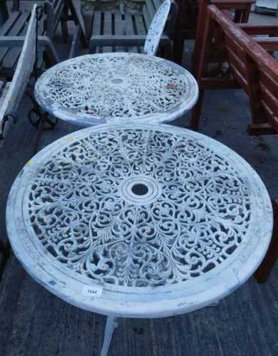 Two Victorian style iron patio tables, each with scroll and floral tops, on entwined stems,...