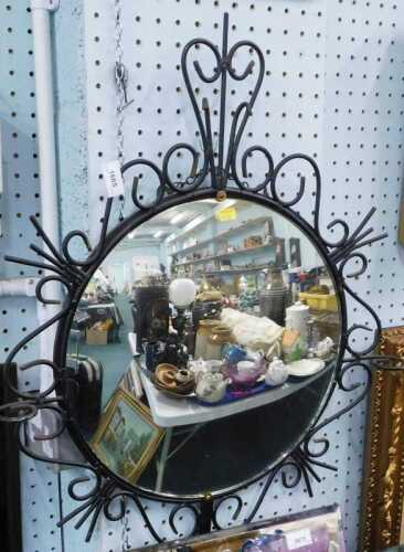 A wrought iron mirror, with raised circular glass.