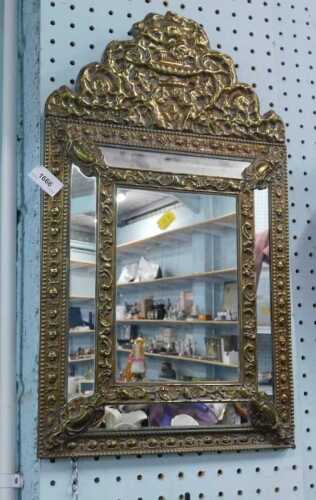 A highly elaborate gilt metal mirror, with stepped rectangular glass centre, the border raised...