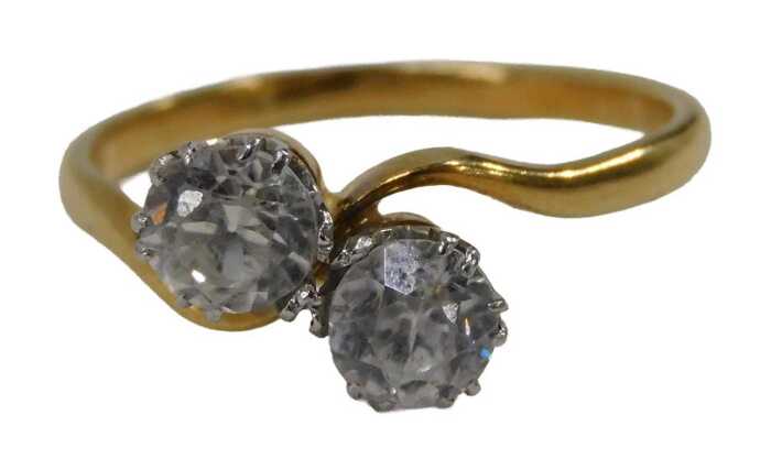 A two stone dress ring, set with two round brilliant cut imitation diamonds, in platinum claw...