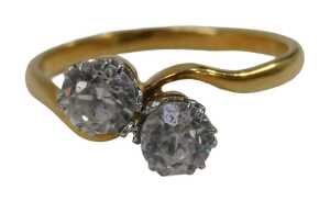 A two stone dress ring, set with two round brilliant cut imitation diamonds, in platinum claw...