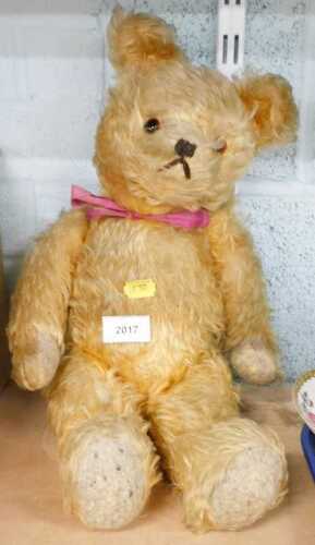 A gold coloured Teddy bear, with jointed head, arms and legs, glass eyes, and felt pads, 46cm high.