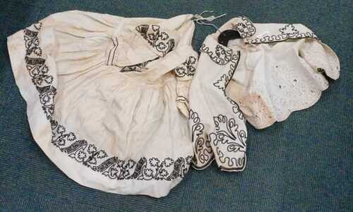 A late 19thC child's worked dress, with shawl decorated with a floral pattern, 54cm high.