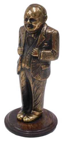 A standing brass figure of Winston Churchill, in jacket and trousers, on oak base, 26cm high.