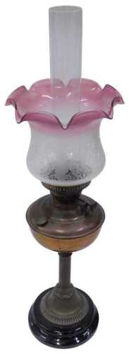 An early 20thC brass oil lamp, with clear funnel, pink frosted and clear glass floral shade and...