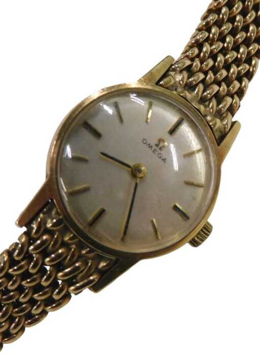 A 9ct gold Omega ladies wristwatch, with a silvered and baton watch face, on a full bar bracelet,...