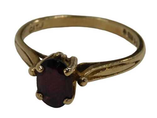 A 9ct gold garnet dress ring, the oval cut garnet in a four claw raised basket setting, ring...