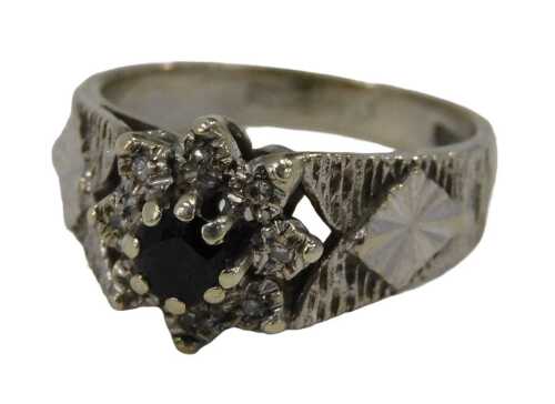 A 9ct white gold cluster ring, the central sapphire surrounded by eight tiny diamonds, on...