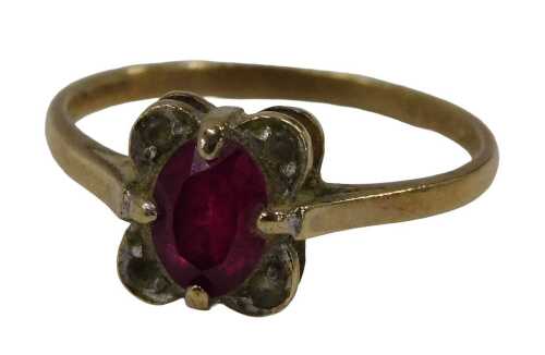 A 9ct gold dress ring, centred with an oval cut garnet and flanked by four CZs, in a petalated...