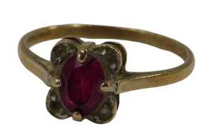 A 9ct gold dress ring, centred with an oval cut garnet and flanked by four CZs, in a petalated...