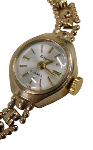 A 9ct gold Accurist ladies wristwatch, with a silvered baton dial, and a hammered link bracelet,...