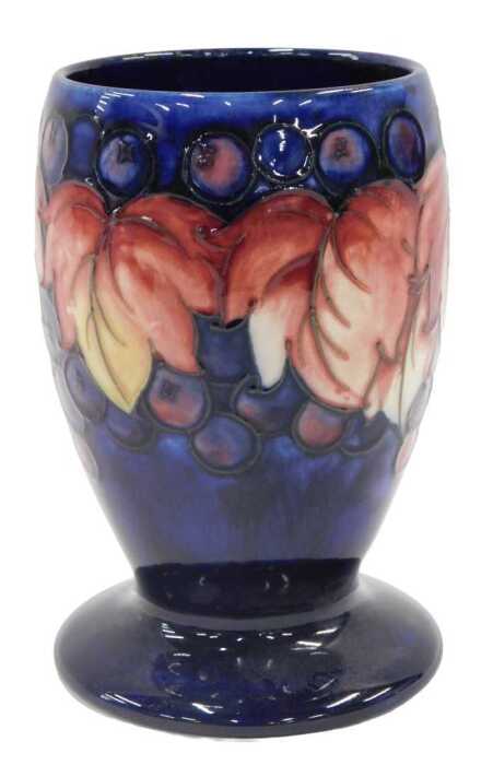 A Moorcroft pottery Leaf and Berry pattern goblet vase, on blue ground, 15cm high.