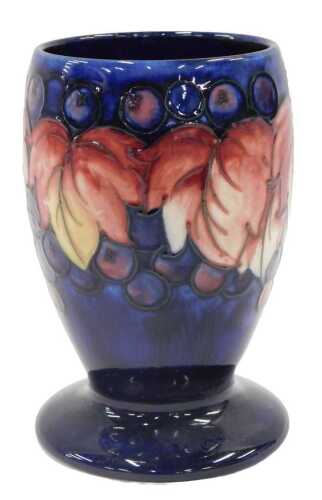A Moorcroft pottery Leaf and Berry pattern goblet vase, on blue ground, 15cm high.