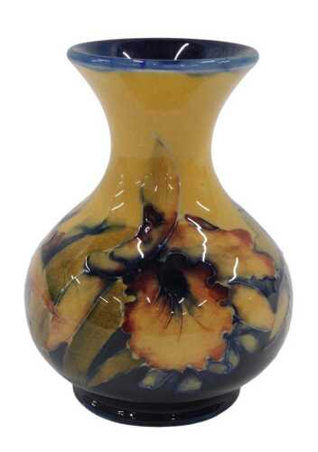 A Moorcroft pottery Hibiscus pattern vase, on ochre ground, of bulbous form on circular foot,...