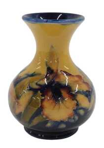 A Moorcroft pottery Hibiscus pattern vase, on ochre ground, of bulbous form on circular foot,...