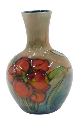 A Moorcroft pottery Freesia pattern vase, of bulbous form with cylindrical stem, on a green...