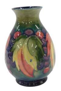 A Moorcroft pottery Leaf and Berry pattern vase, of shouldered form on circular foot, on green...