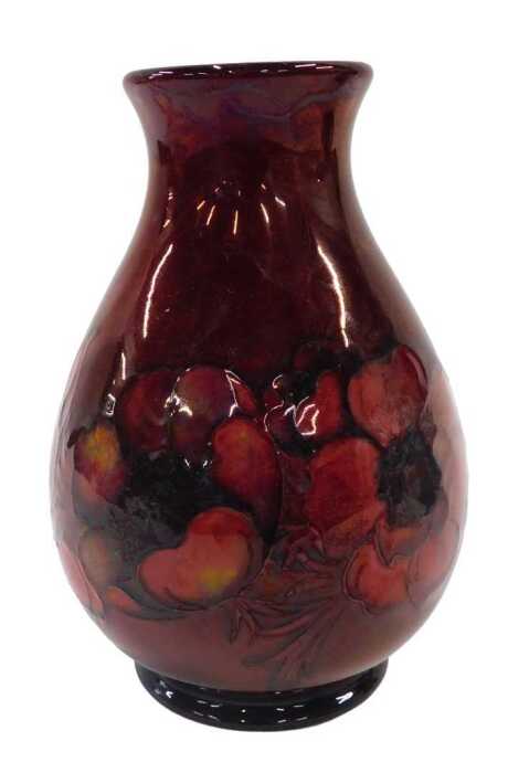 A Moorcroft pottery flambe Anemone pattern vase, of shouldered form on circular foot, on red...
