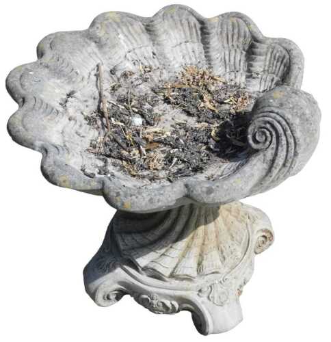 A 20thC classical design stone birdbath, with rococo style shell top, on a platform base...
