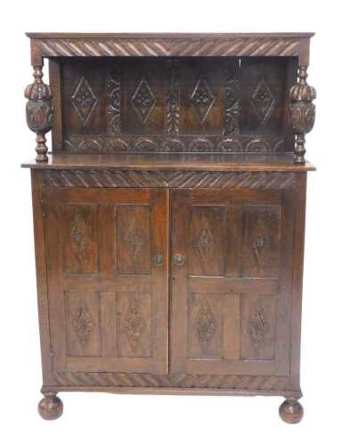 An 18thC style oak court cupboard, the upper section with heavily carved canopy, held on heavy...