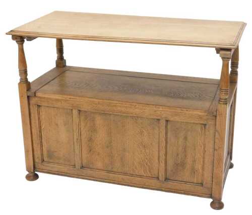 A 20thC oak monk's bench, with table back and log box seat, with plain three panelled front, on...