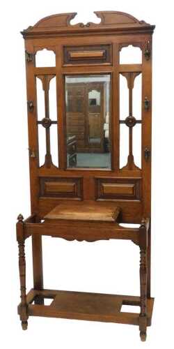 An Edwardian oak hall stand, the heavily carved upper section centred by a mirror, flanked by...