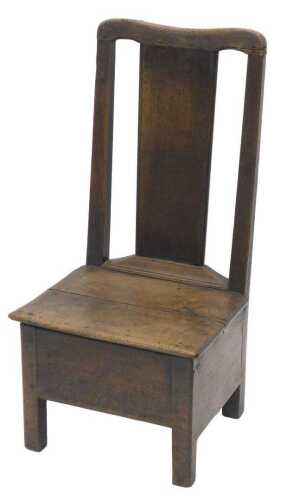 An 18thC oak lambing chair, with serpentine cresting rail and plain splat, above a panelled seat,...