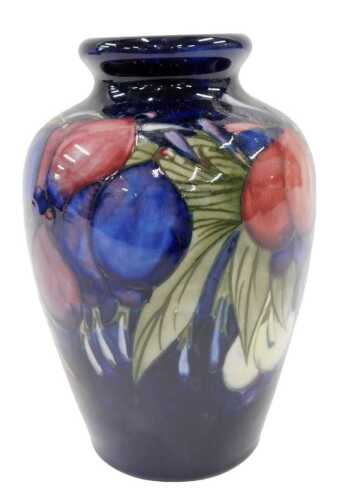 A Moorcroft pottery Wisteria Plum pattern vase, of circular shouldered form, on blue ground,...