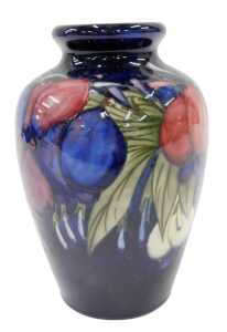 A Moorcroft pottery Wisteria Plum pattern vase, of circular shouldered form, on blue ground,...