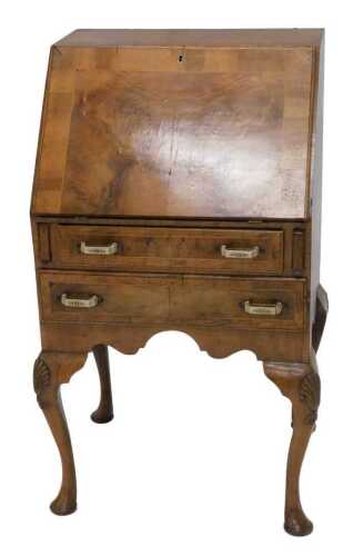 A 1920s walnut bureau, the half veneered fall revealing an arrangement of pigeon holes, above...