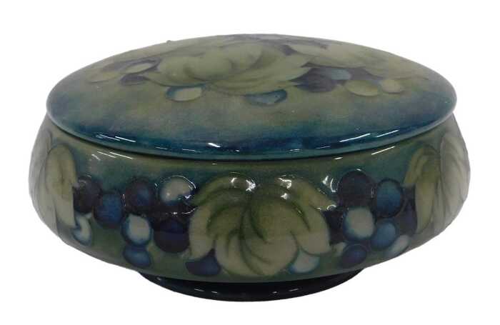 A Moorcroft pottery Leaf and Berry pattern jar and cover, of compressed circular form, on green...