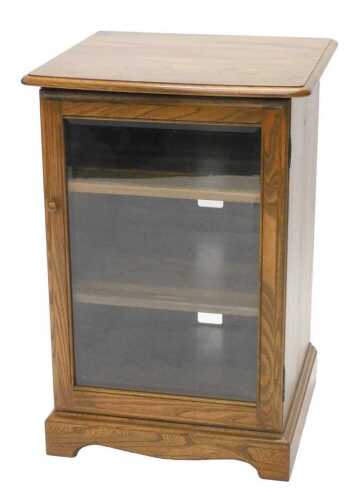 A late 20thC Ercol hi-fi cabinet, the rounded top raised above a single glazed door, revealing...