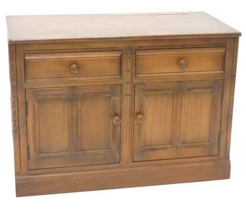 A late 20thC Ercol low side cabinet, of rectangular form, the studded top raised above two...