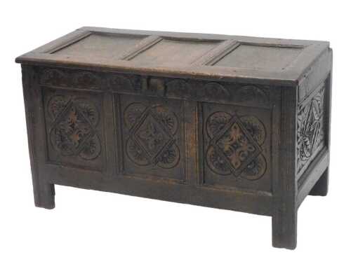 A 17thC oak three panelled coffer, of rectangular form, the heavily carved lid revealing a plain...