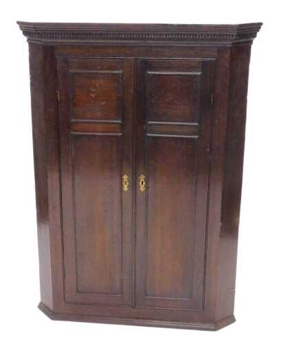 An 18thC oak hanging corner cupboard, the panelled doors revealing a fitted interior of...