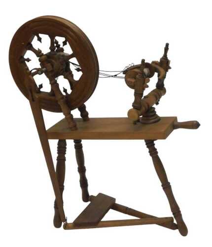 A 20thC beech spinning wheel, with articulated top, on a platform base, terminating in turned...