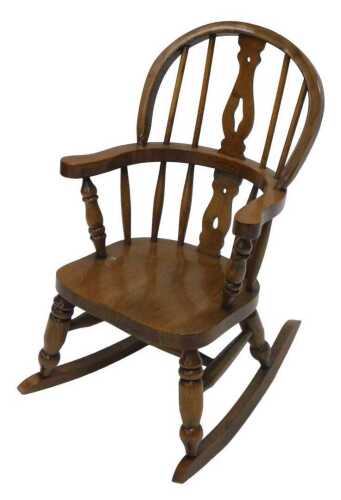 A 20thC ash and elm child's Windsor rocking chair, with pierced backsplat, shaped arms and ring...