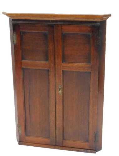 A 19thC oak hanging corner cupboard, the two panelled doors revealing a fitted interior, with...